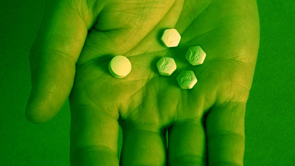 Hand holding one mifepristone and four misoprostol pills